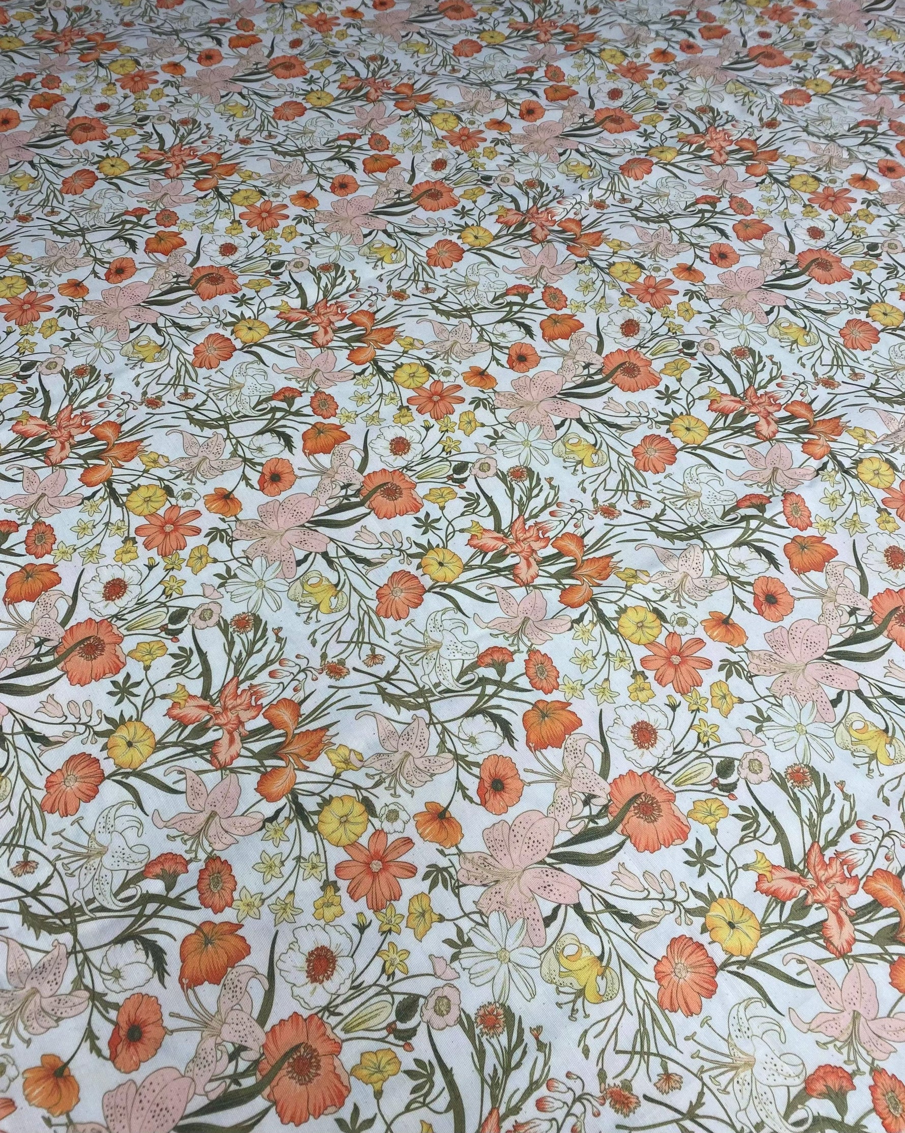 Orange floral patterned linen fabric with vibrant flowers and greenery for sewing and crafting projects