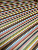 Multicolor striped woven fabric with vibrant green and pastel tones, perfect for sewing garments and creative projects