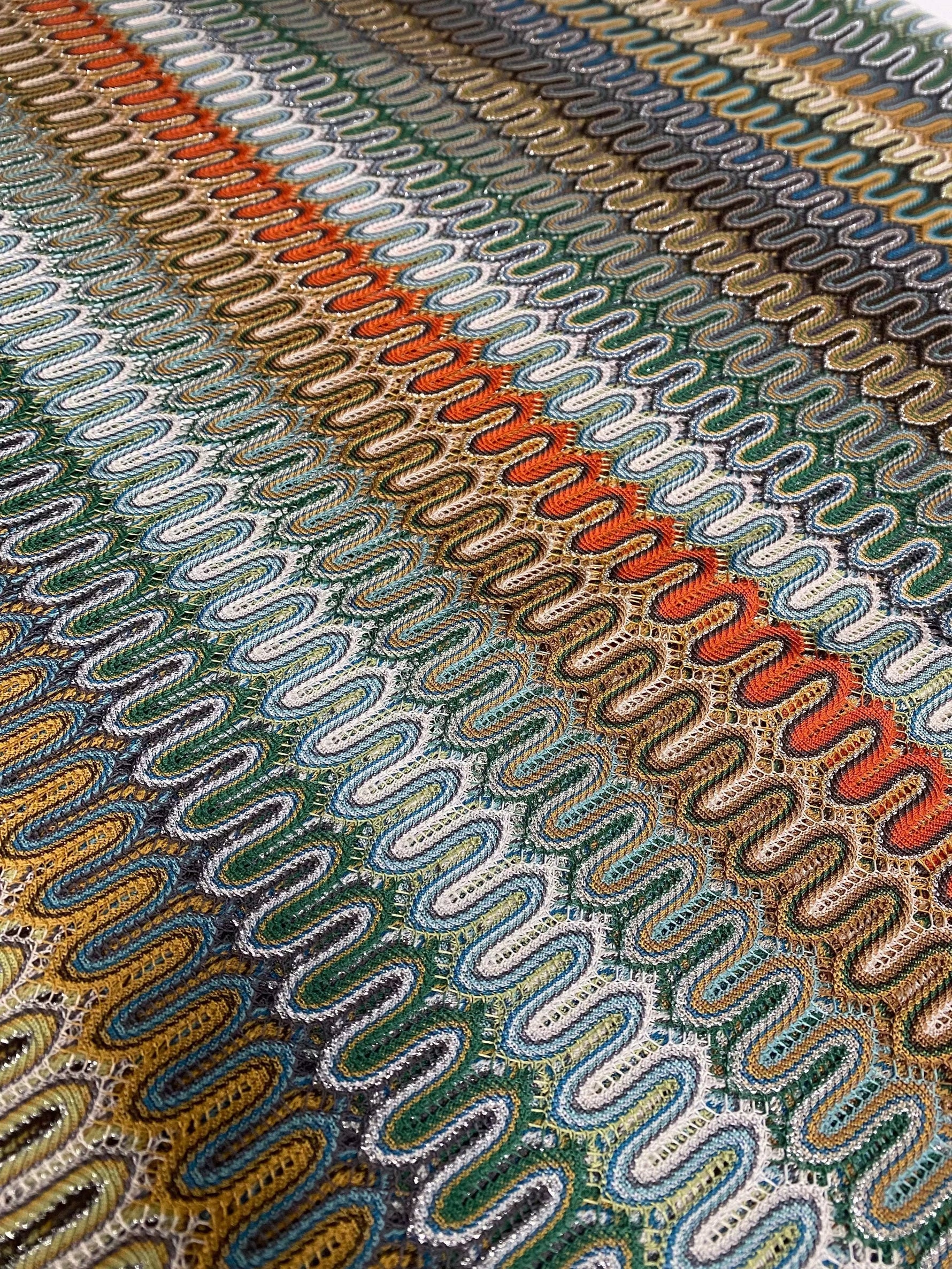 close-up of colorful mesh zigzag knit fabric with varied zigzag patterns in multiple colors and breathable texture