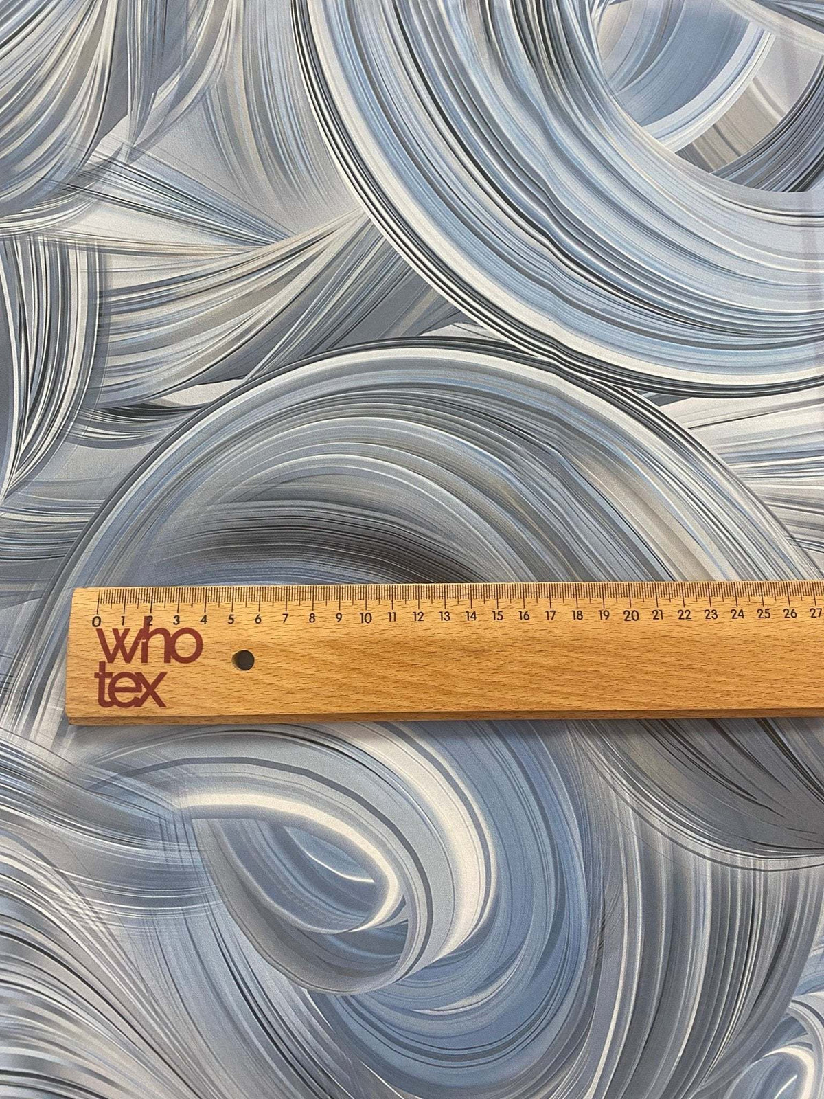 abstract swirl pattern fabric in neutral tones with modern brushstroke design and wooden ruler for scale