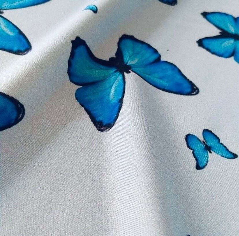 Soft baby blue fabric with vibrant blue butterfly prints for sewing projects