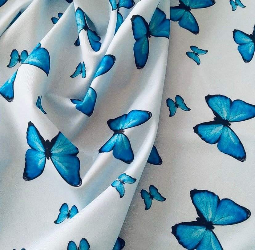 Soft baby blue fabric with vibrant blue butterfly print for sewing projects