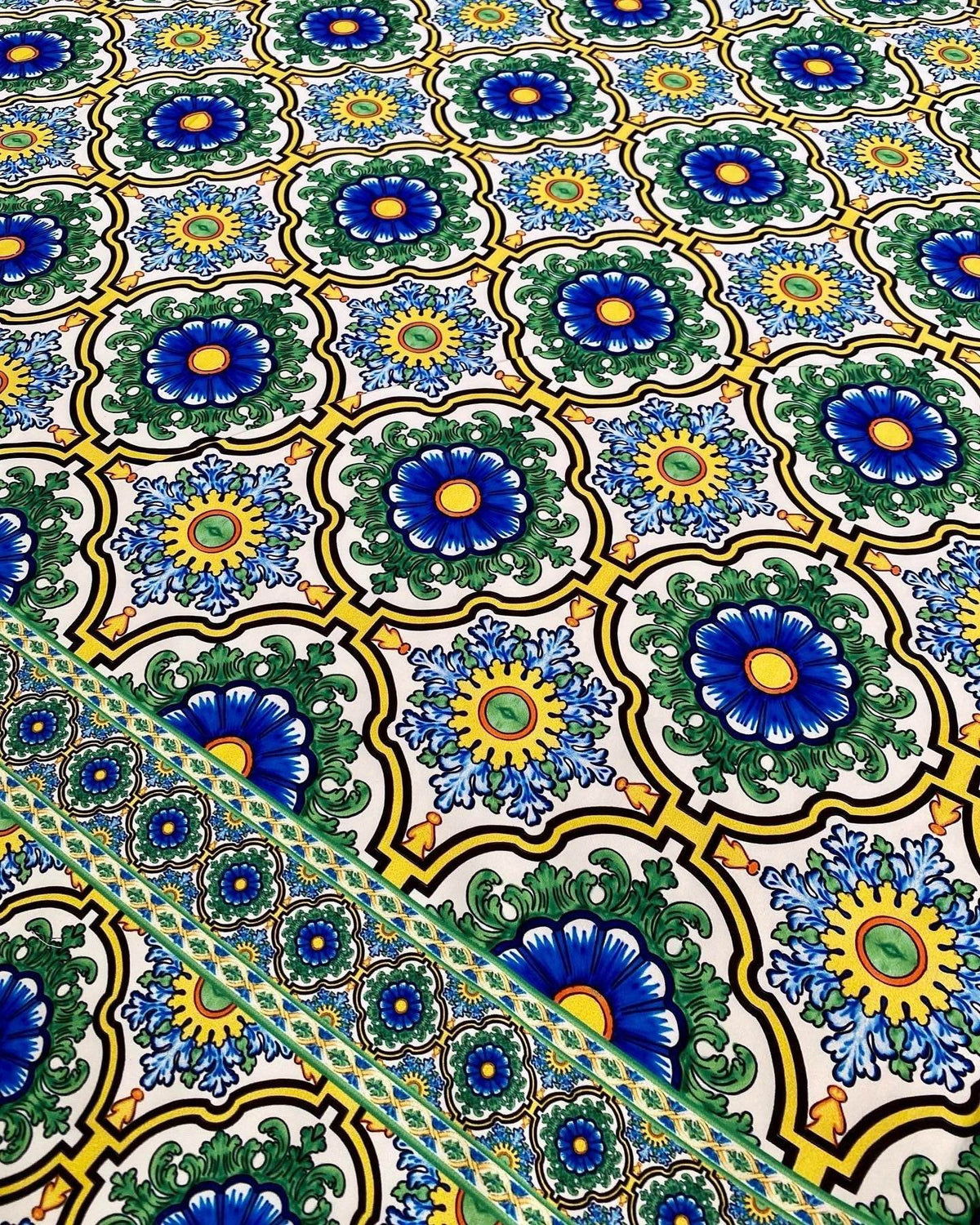 Sicilian pattern green fabric with intricate blue and yellow floral designs on a white background, ideal for sewing and upholstery projects