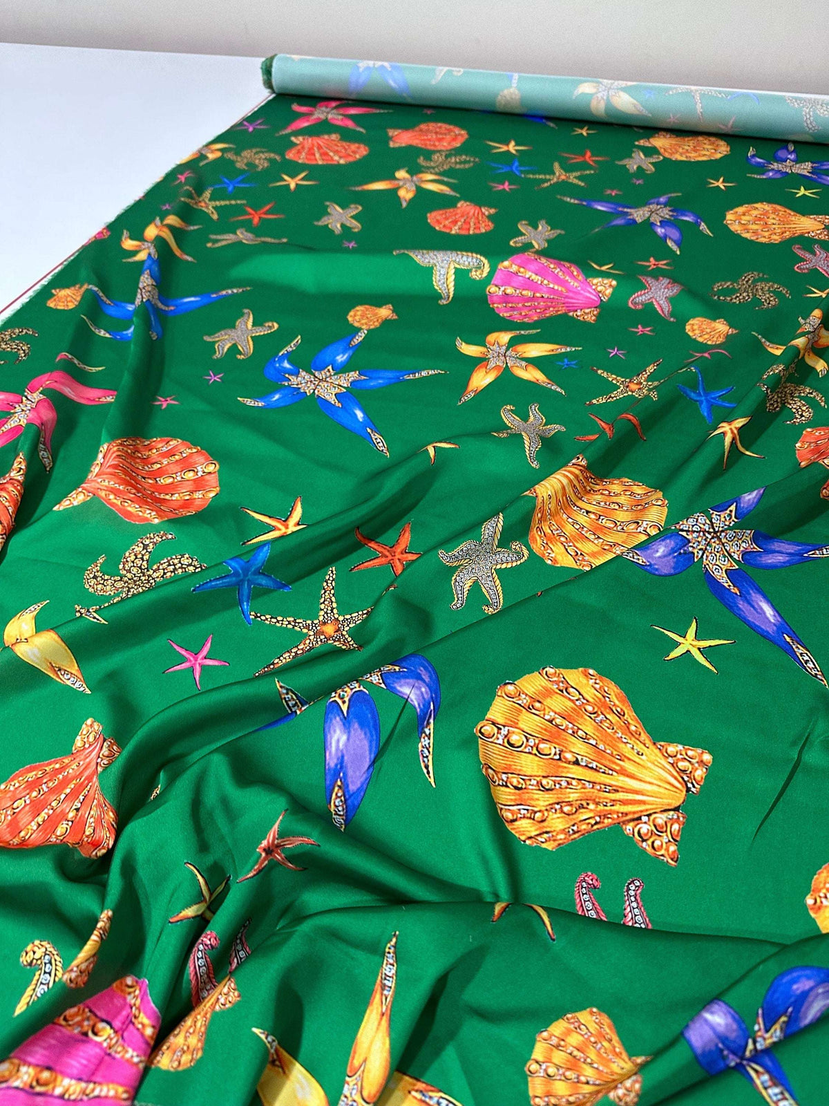 Green fabric with colorful sea shell and starfish pattern for coastal decor and crafting projects