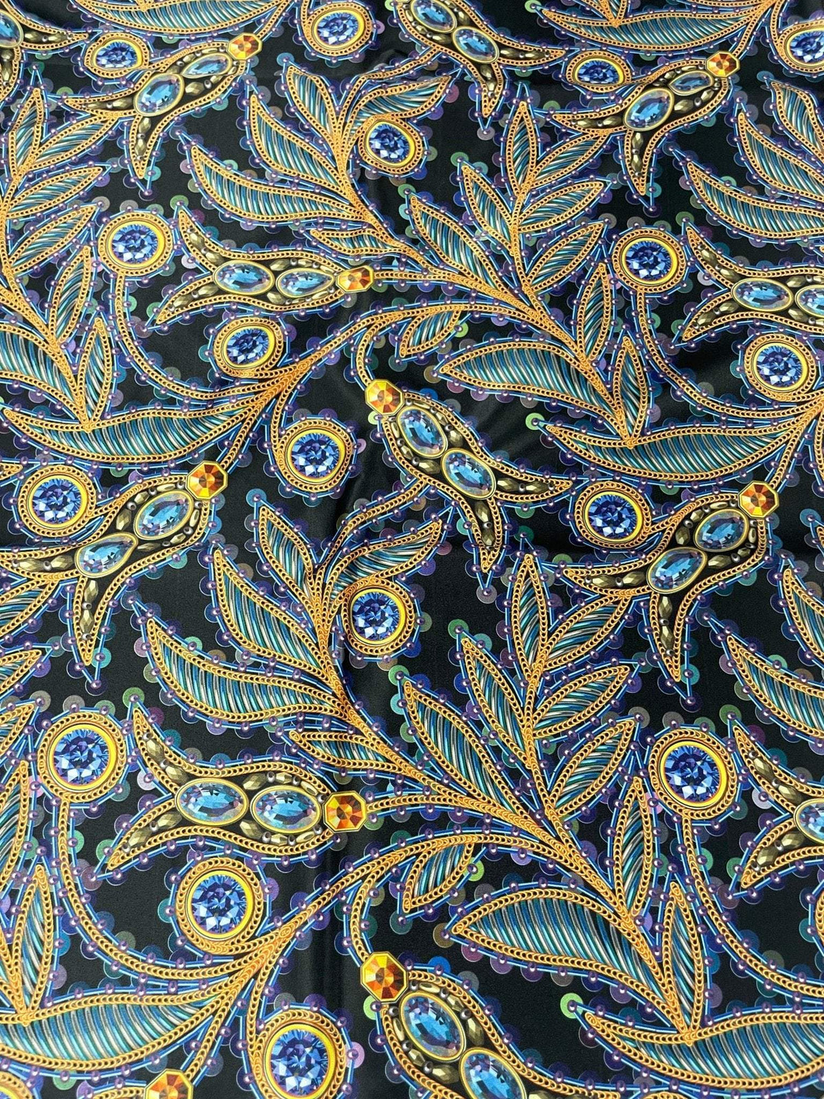 Luxury peacock feather fabric with jewel accents in vibrant blue and gold on black background