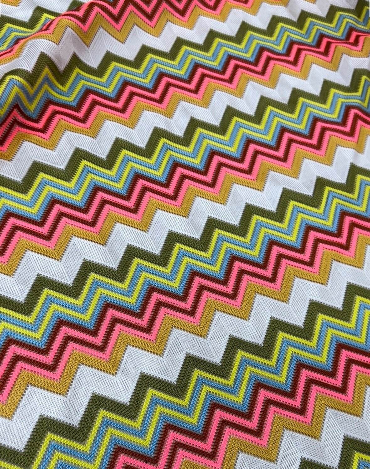 Multicolor zigzag knit jersey mesh fabric with vibrant zigzag pattern in pink, yellow, olive, and blue for crafting and apparel projects