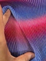 Close-up of pleated power mesh fabric in shimmering gradient shades of purple, blue, and pink held by hand