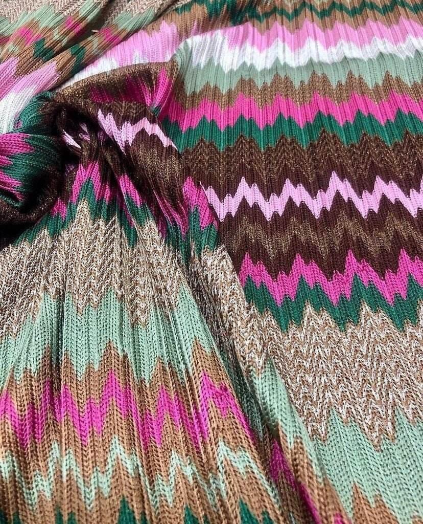 Close-up of shiny zigzag knit jersey mesh fabric with pink, green, brown, and beige patterns
