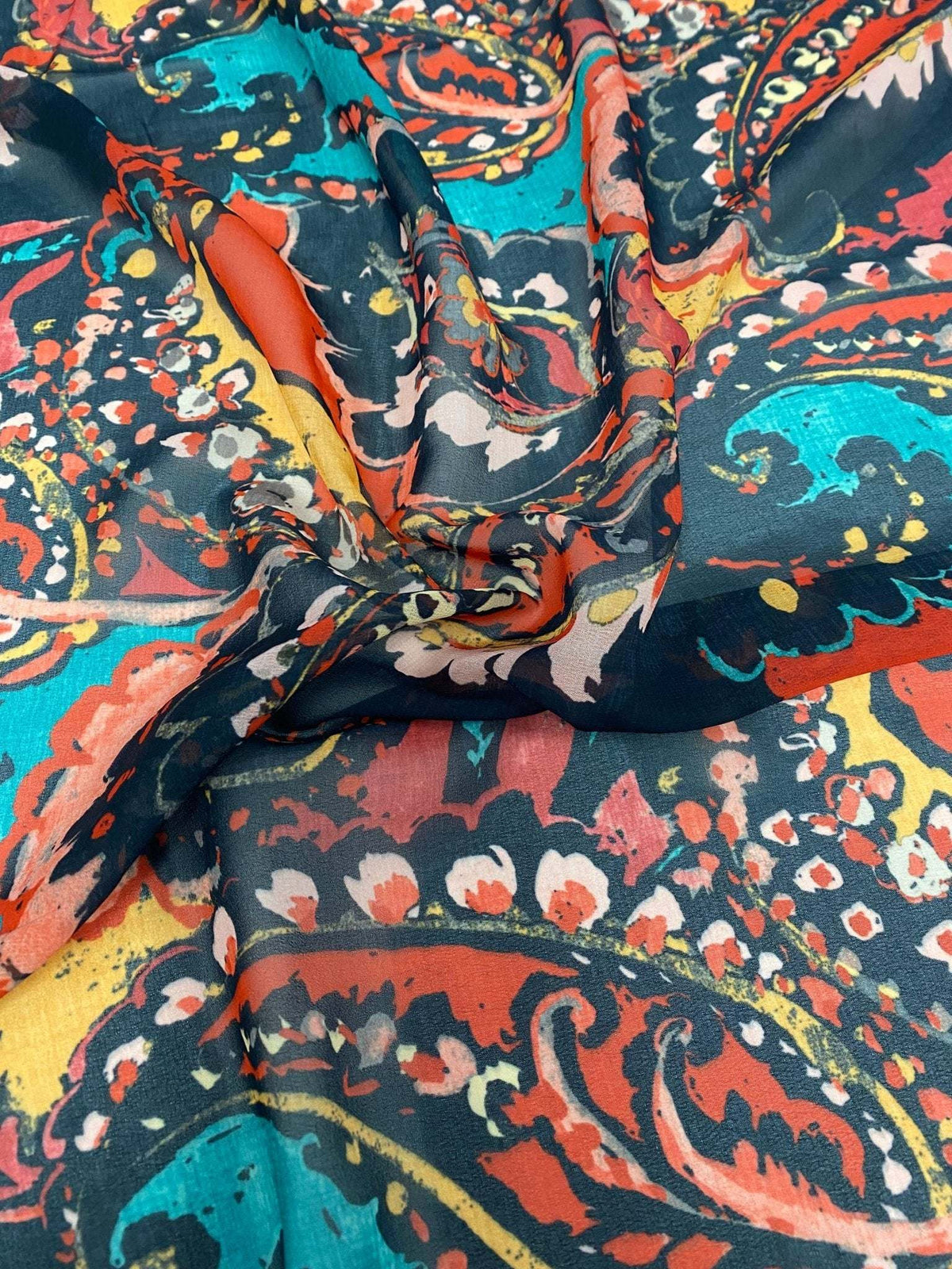 Close-up view of vibrant multicolor paisley print fabric with orange, teal, and black tones
