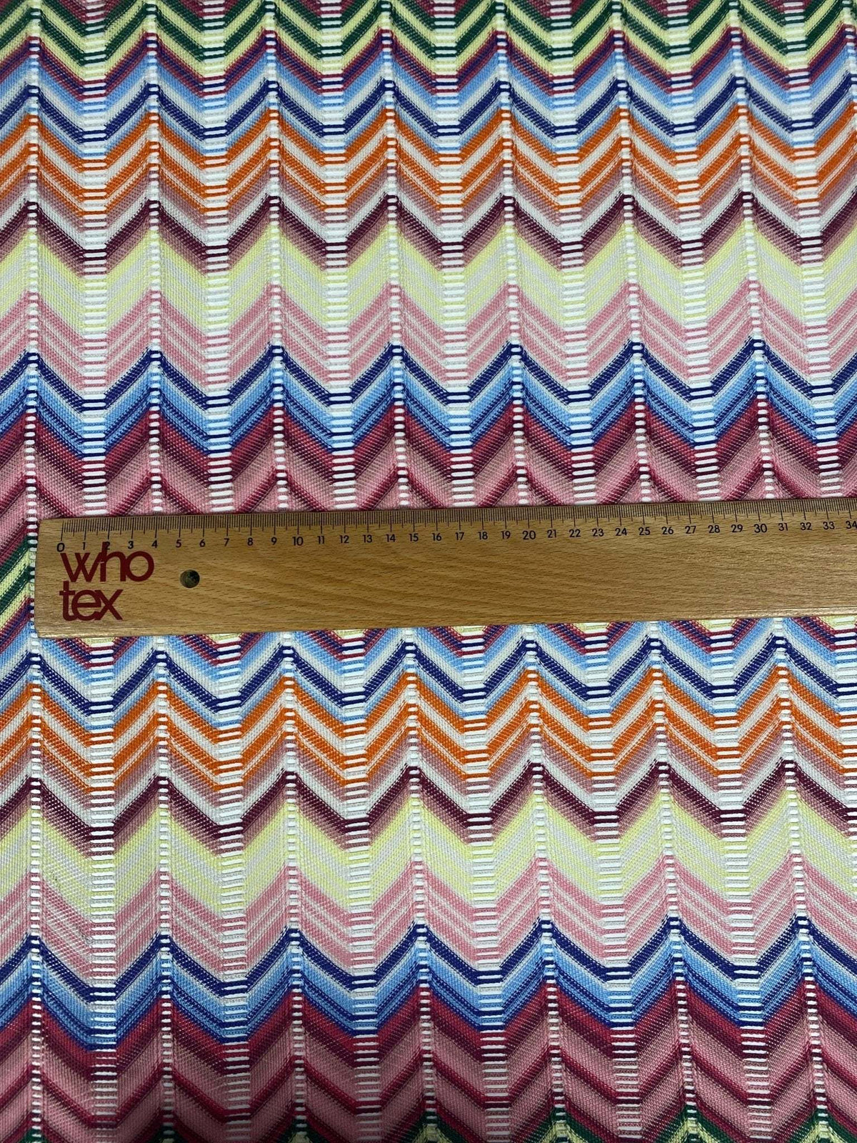 Pastel multicolor chevron mesh fabric with zigzag knit pattern and ruler for scale