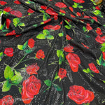 Black fabric with red rose pattern and green leaves, covered in shimmering sequins with two-way stretch, ideal for elegant evening wear.