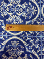 Close-up of blue and white Sicilian print fabric with intricate floral and geometric patterns and a wooden ruler for scale