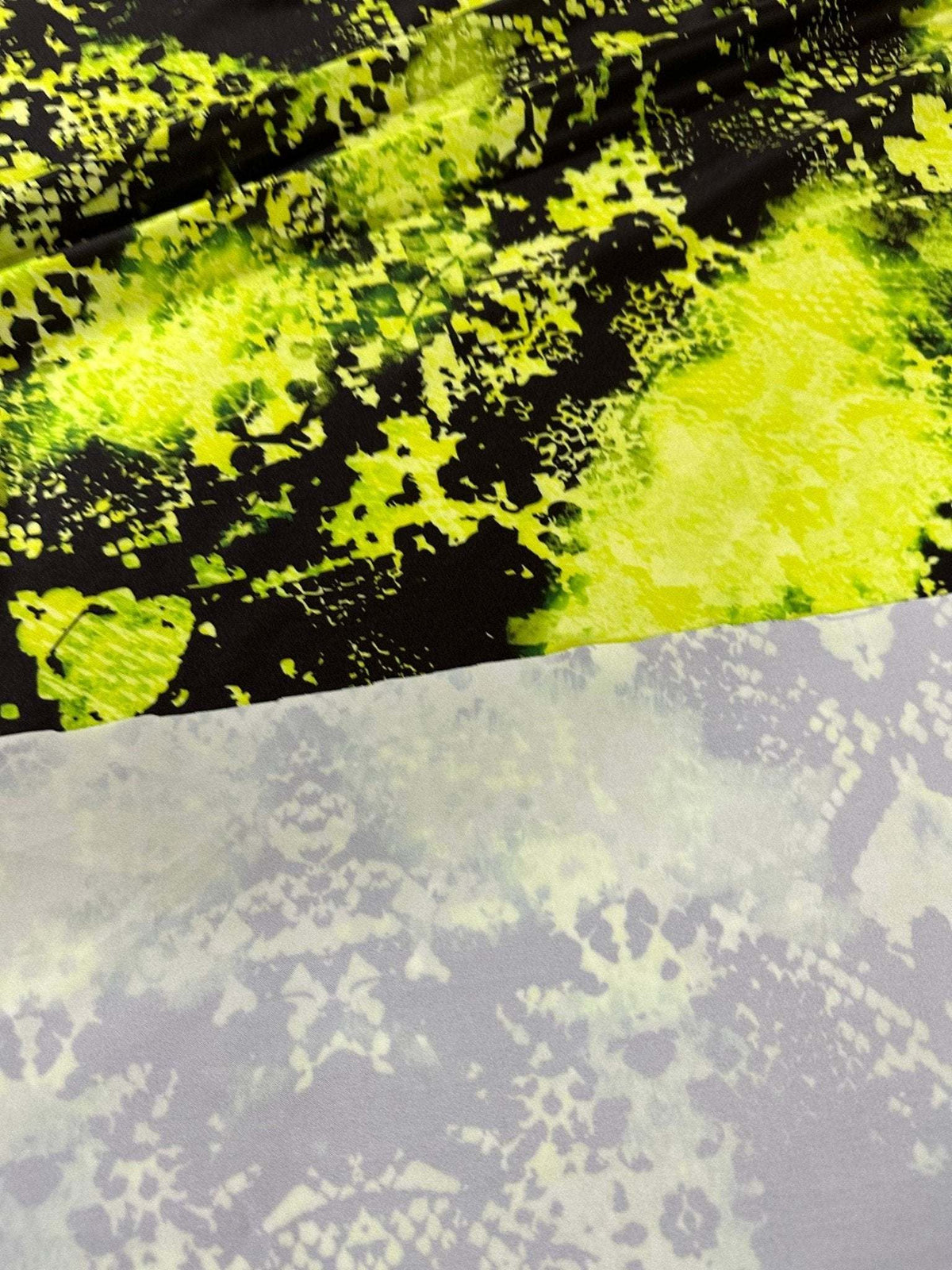 Close-up of vibrant neon green spandex fabric with black and gray abstract patterns suitable for activewear and costumes