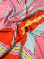 Close-up of retro psychedelic swirl and sun print fabric with vibrant pink, red, yellow, and blue colors