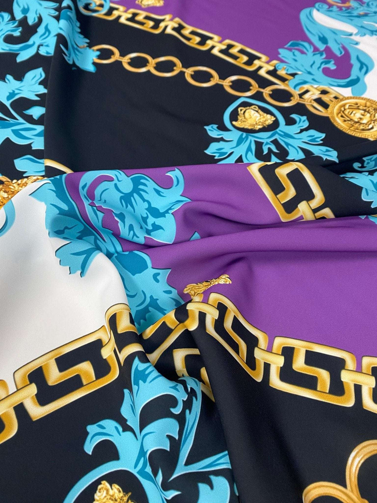 Swirl pattern crepe fabric with gold chain print in black, purple, white, and blue colors, lightweight and flowy texture
