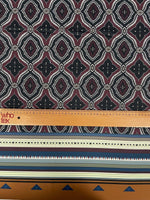 Burgundy and black geometric patterned fabric with ethnic striped edge and measuring ruler for scale