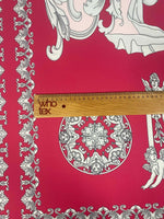 Pink vintage Baroque fabric with intricate cherub and ornate pattern next to a wooden ruler showing scale